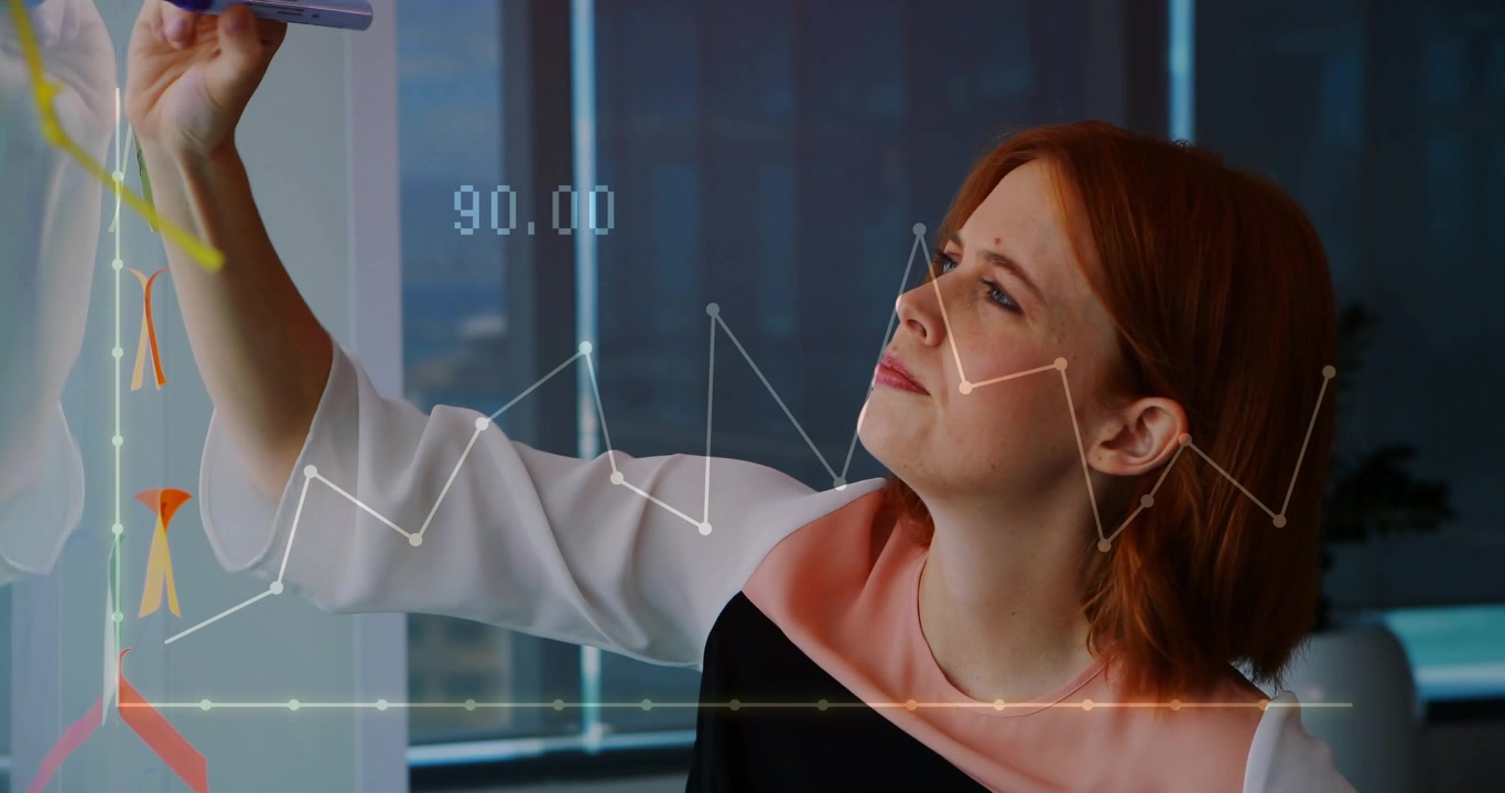 Female business analyst raising marker, drawing line graphs on glass and analyzing numeric overlay