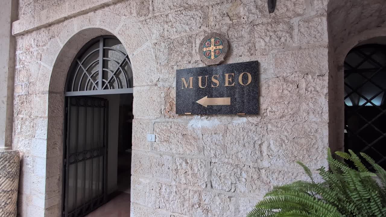 Slow zoom in on the stone entrance and “Museo” sign at Monte Cassino Abbey in Italy, showing historic architecture and the path toward the museum interior