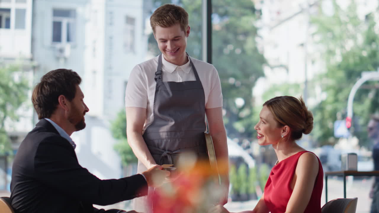 Smiling boyfriend paying restaurant bill using credit card. Romantic couple date