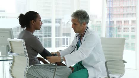 mature doctor examining his patients blood pressure