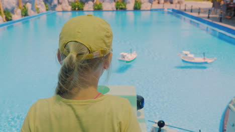 Mädchen,-Das-Auf-Einer-Spielzeugboot-Fahrtsteuerung-Spielt,-Die-Im-Pool-4k-Video-Schwimmt