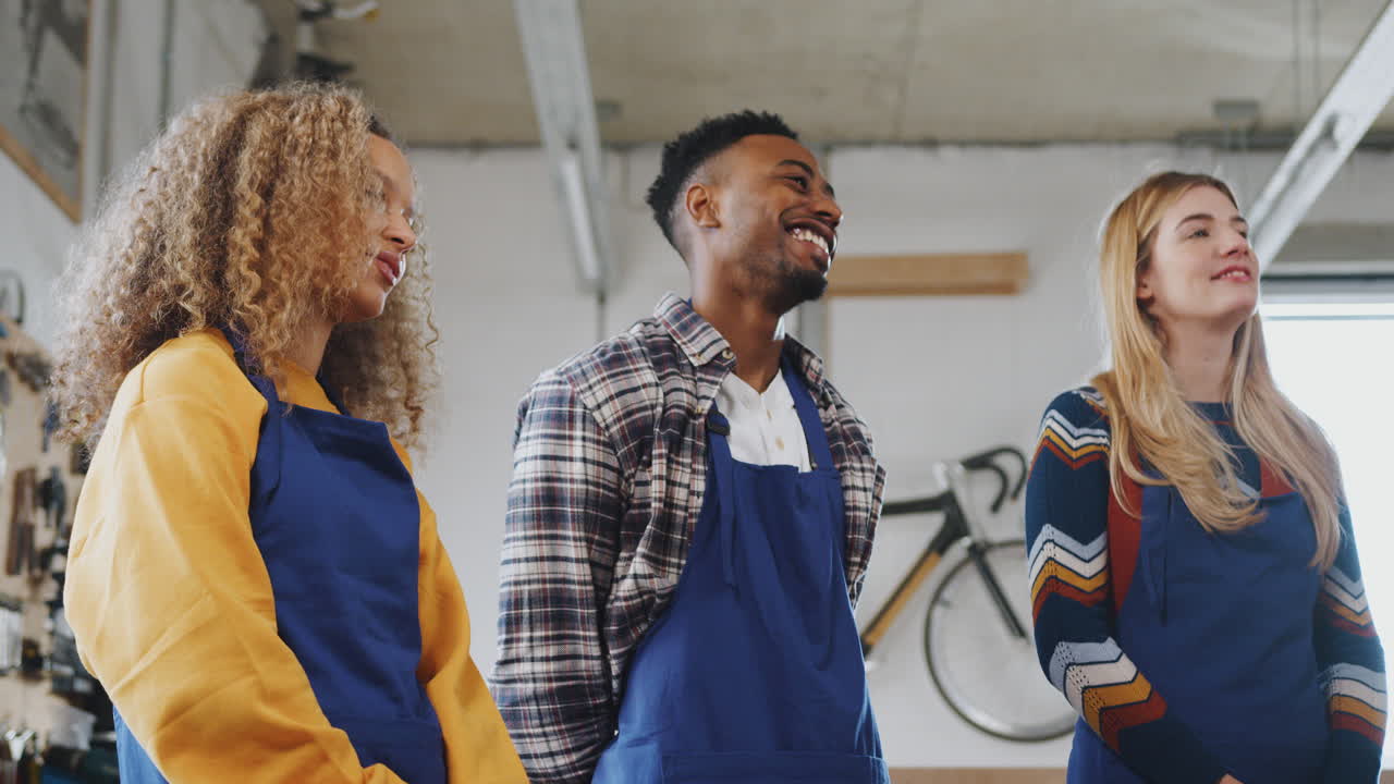 Multi-Cultural Team Of Trainees In Workshop Learn How To Assemble Hand Built Bicycle Frame Together