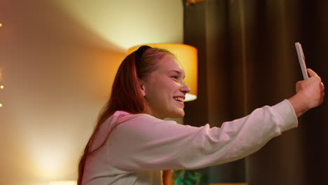 mujer sonriente tomando una selfie en su dormitorio