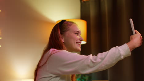 smiling woman taking a selfie in her bedroom