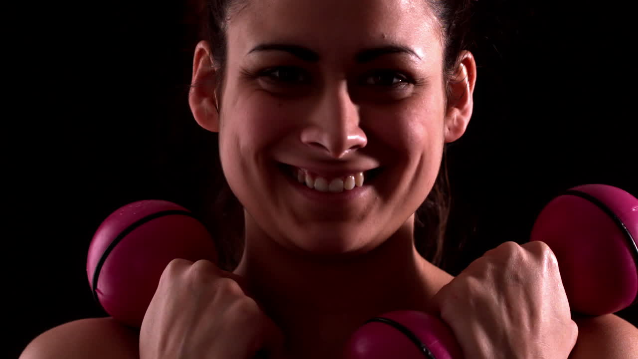 mujer en forma sonriente levantando pesas