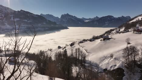 a stunning winter view from amden, switzerland, overlooking the walensee valley, where a thick sea of fog blankets the landscape. snow-covered hills and alpine homes.