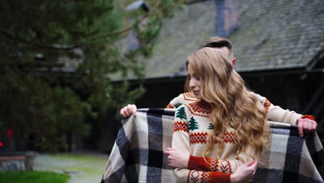 young handsome man covers beautiful girl with blanket outside. same sweters. love story video.
