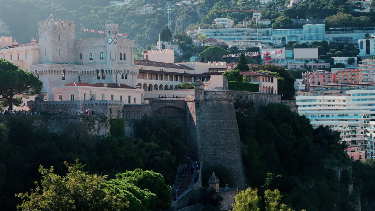 Distant view of the Prince's Palace of Monaco with people walking through the court