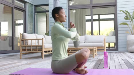 focused biracial woman practicing yoga and meditating in garden, slow motion