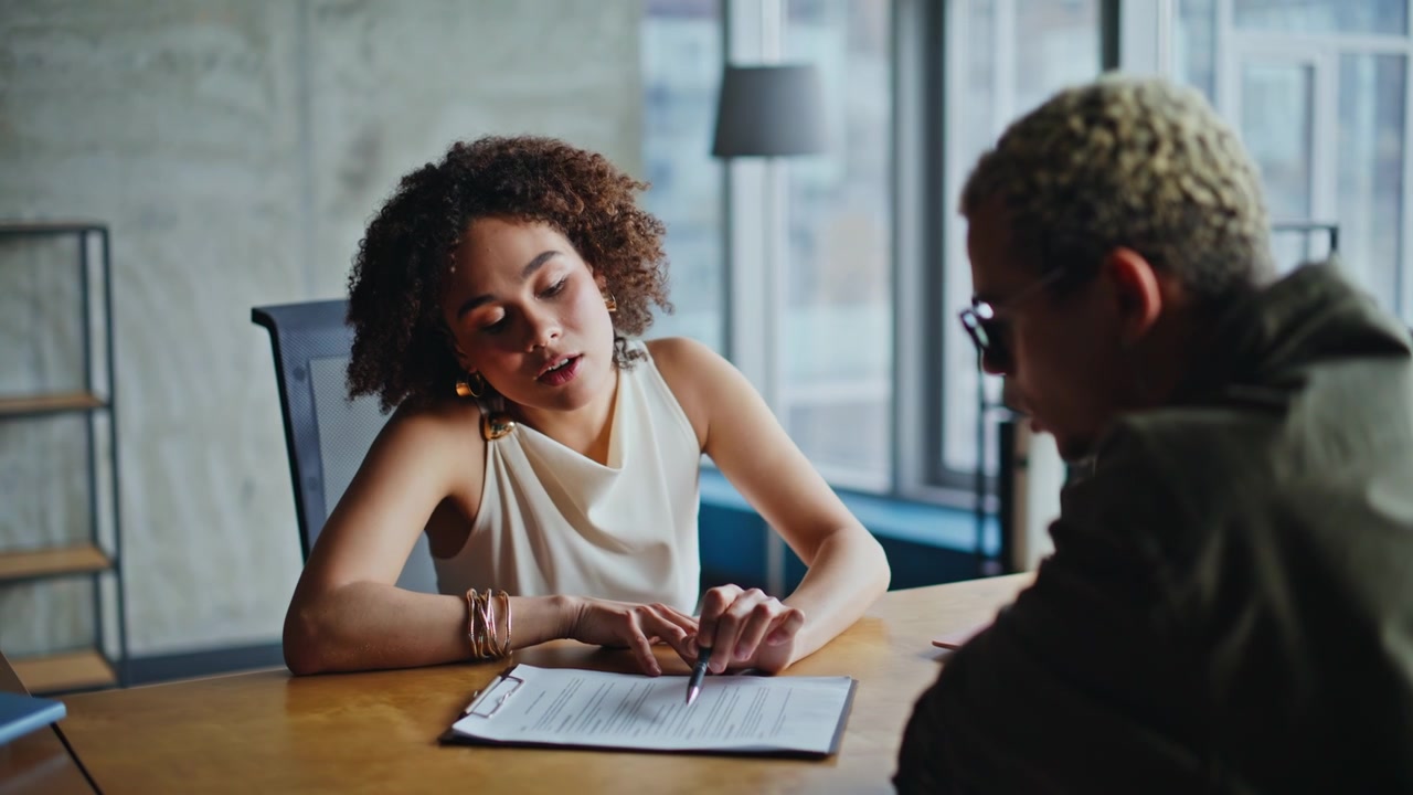 Businesswoman explaining contract to client in office meeting reviewing files