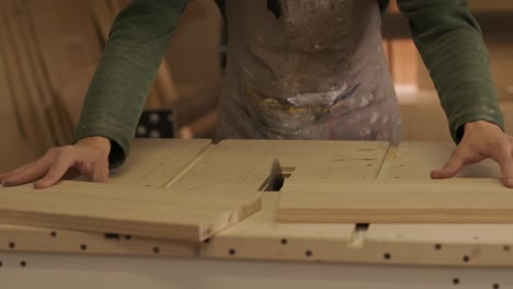 el carpintero corta tabla de madera, panel de contrachapado, madera en bruto en el taller utilizando una máquina de corte