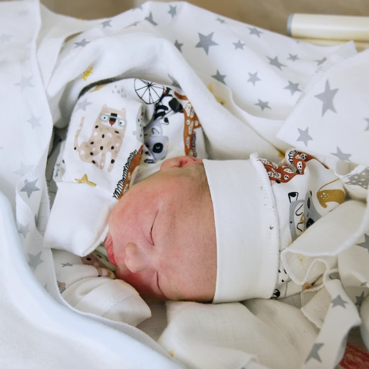 Vista dall'alto di un neonato disteso tra le lenzuola. Un neonato carino con cappello e maglietta dorme beatamente