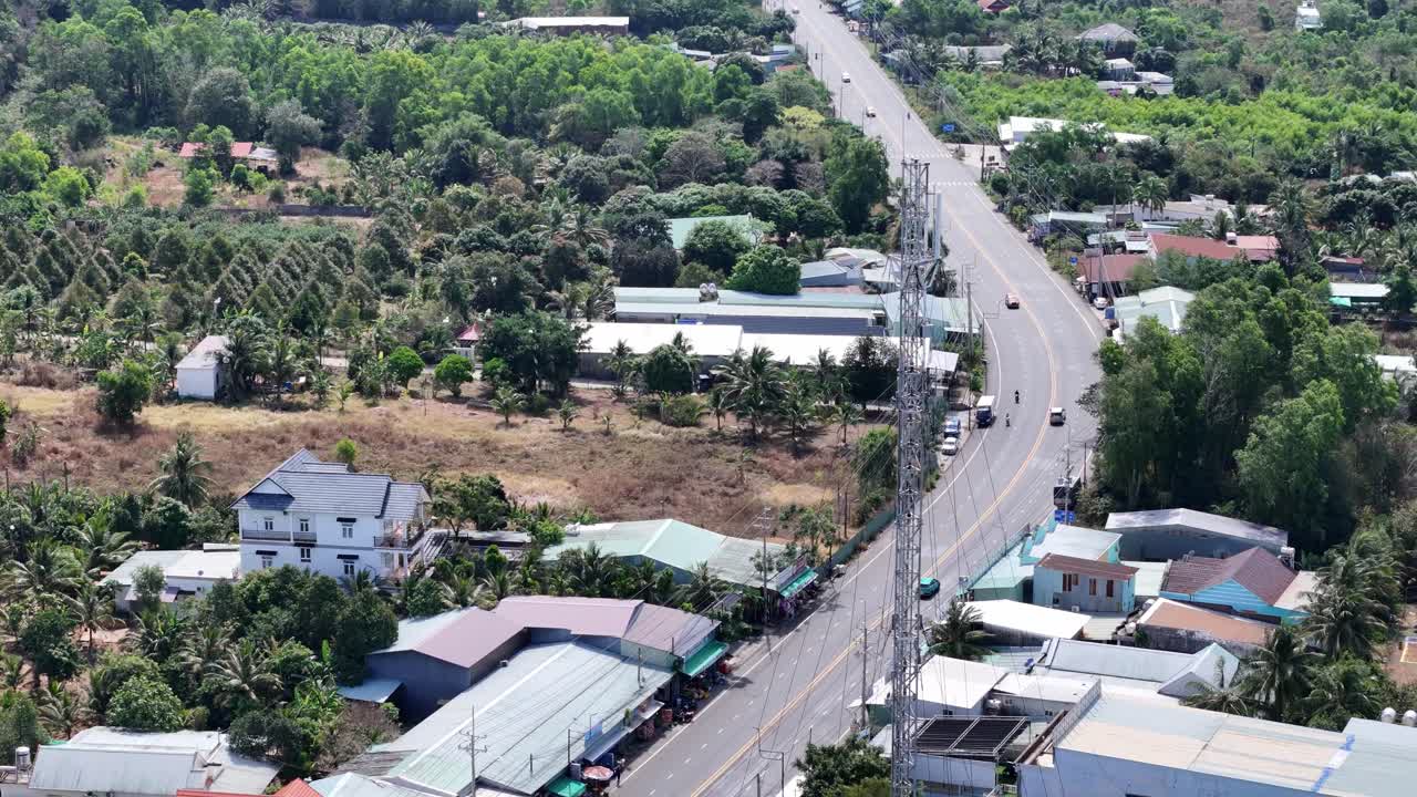 The aerial video opens with a circling shot of an antenna tower, providing a panoramic view before transitioning to a main road by light traffic flow and abundant greenery lining both sides