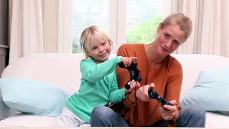 cute little girl playing video games with her mother