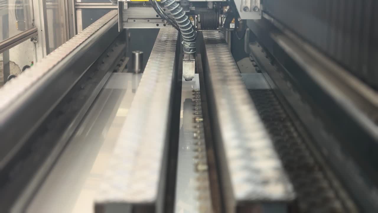 Industrial laser machine welding metal, a robotic mechanism in a factory. Technology concept. A flat sheet of stainless steel is being welded with flashes. Side top view