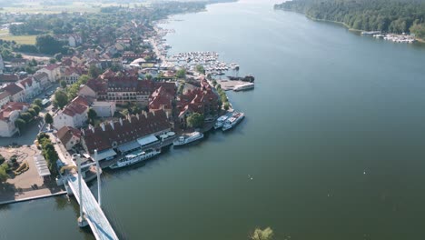 mikolajki, poland - drone flight aerial bird flyover the city center of mikolajki following the coast of the blue lake with restaurants tiny boats and yachts