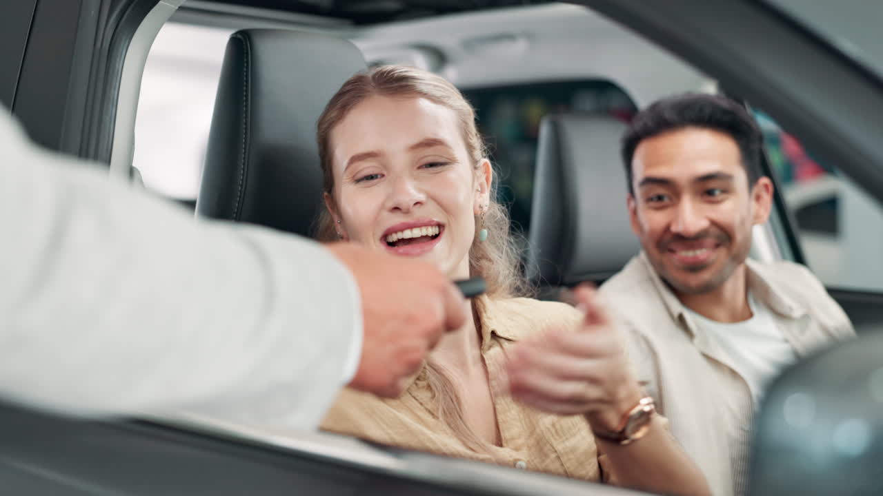 Couple receiving keys for a new car at a dealership