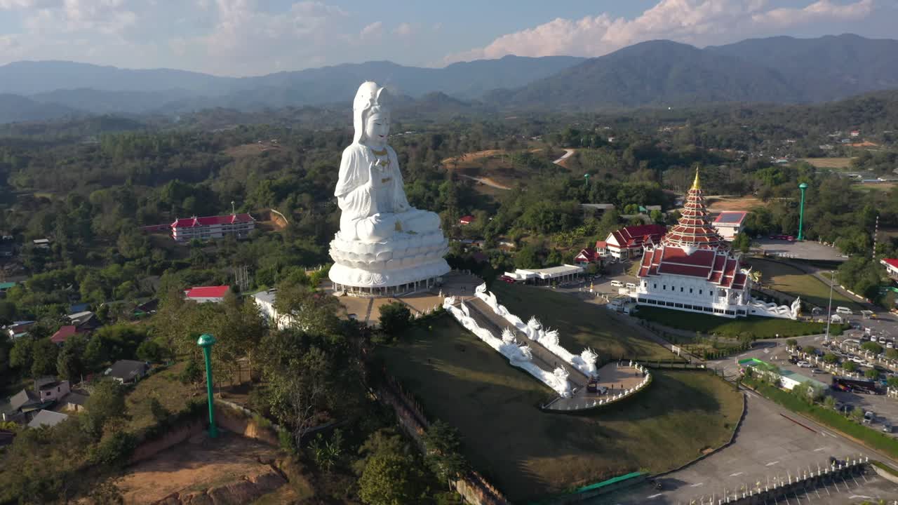 drone aéreo de wat huay pla kang gigante estatua blanca grande y templo de pagoda con montañas y espacio terrestre en chiang rai, tailandia