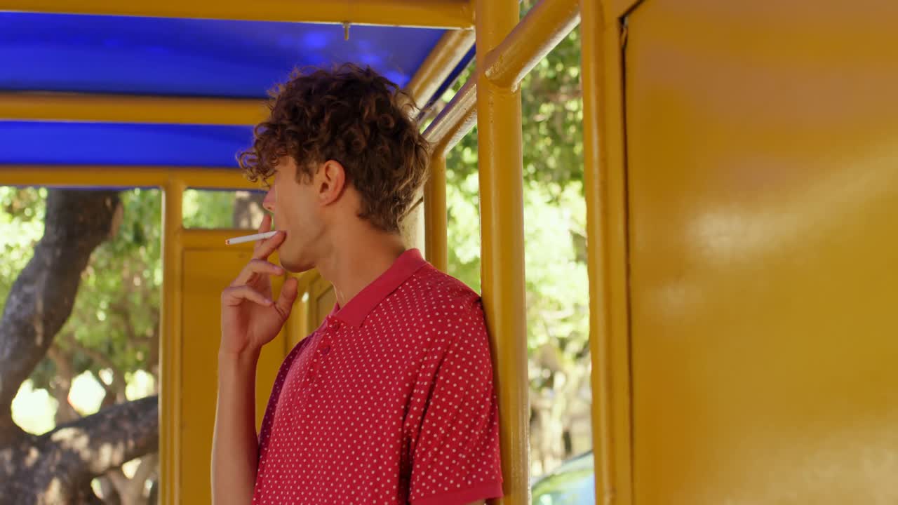 viajero masculino fumando un cigarrillo en la parada de autobús 4k