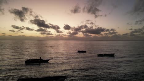 Barcos-De-Pesca-Anclados-En-La-Costa-De-La-Playa-De-Uroa-En-La-Isla-De-Zanzíbar-Durante-La-Puesta-De-Sol,-Tanzania-áfrica-Durante-La-Puesta-De-Sol,-Toma-Aérea-A-La-Derecha