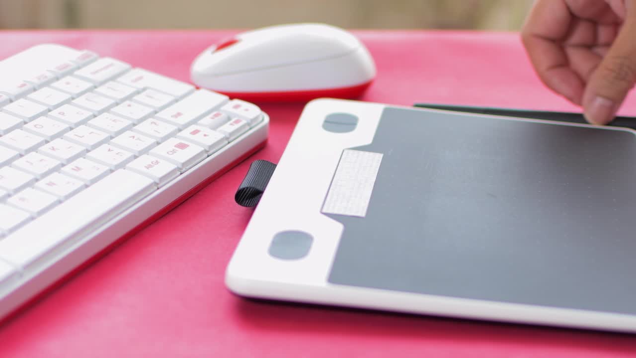 Woman's hand using mouse and graphic tablet to design. On red table.