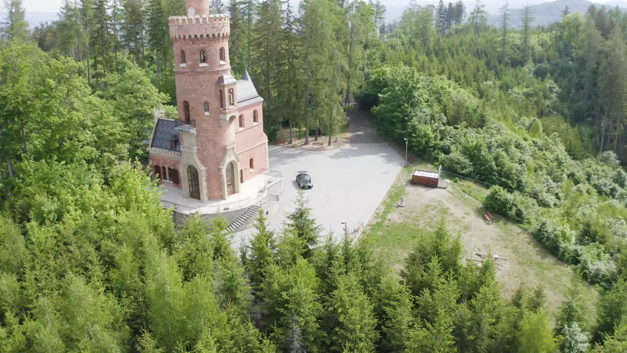 черный спортивный автомобиль припаркован возле небольшого замка в италии - вид с воздуха