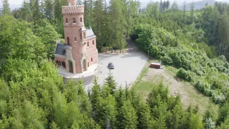 Black-Sports-Car-Parked-Near-a-Small-Little-Castle-in-Italy---Aerial-View