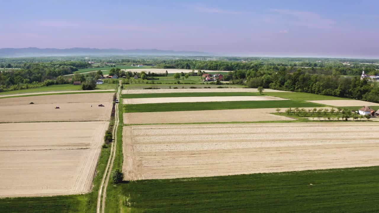 Capturing areal footage of peoples working in field in spring, agricultural field with lots of wheat