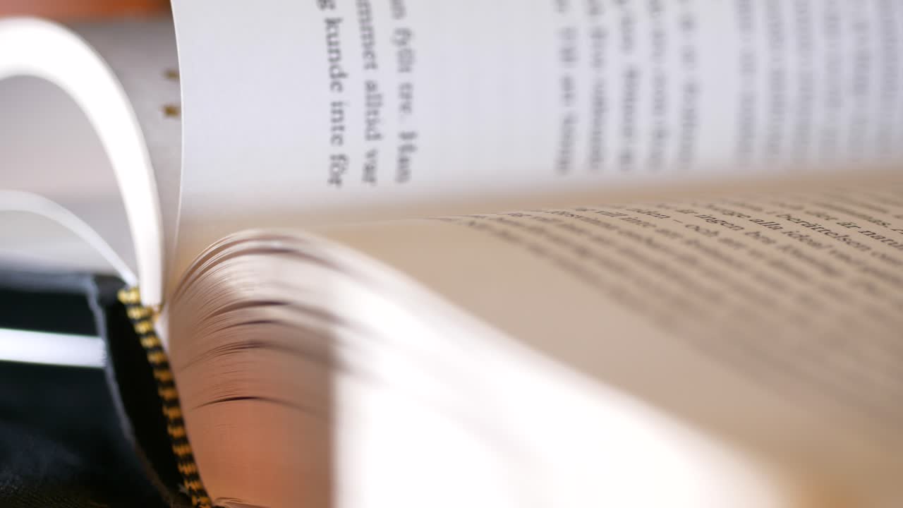 Close up of opened book, hand turning page, slow motion