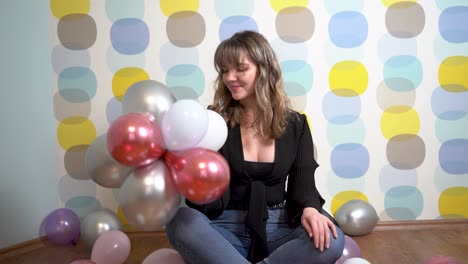 Junge-Frau-Sitzt-Um-Luftballons-Herum-Und-Spielt-Mit-Luftballons-Vor-Buntem-Hintergrund