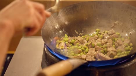 cocinar guisantes con carne en un wok al fuego