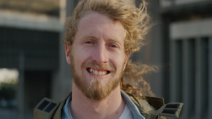 portrait happy young man smiling enjoying relaxed urban lifestyle wind blowing hair bearded hipster male in city at sunset