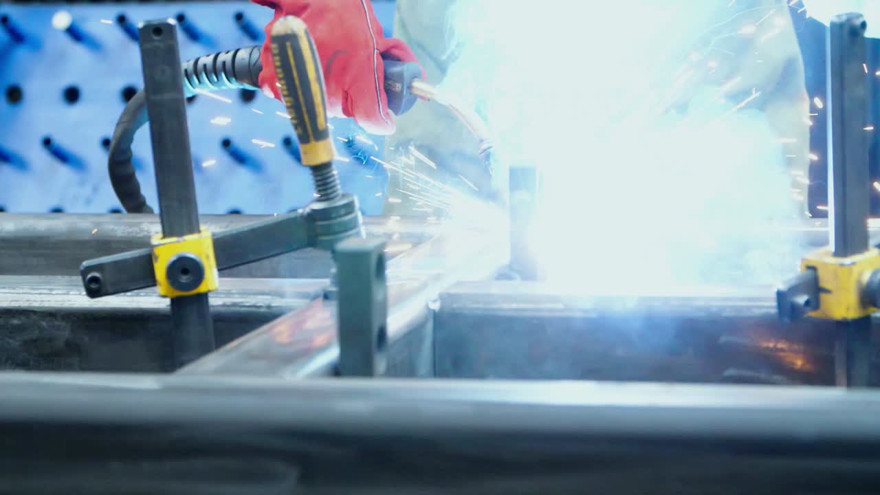 금속 가공 공장의 작업실에서 금속 공백을 용접하는 사람