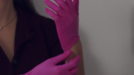 female medical professional putting on pink latex gloves