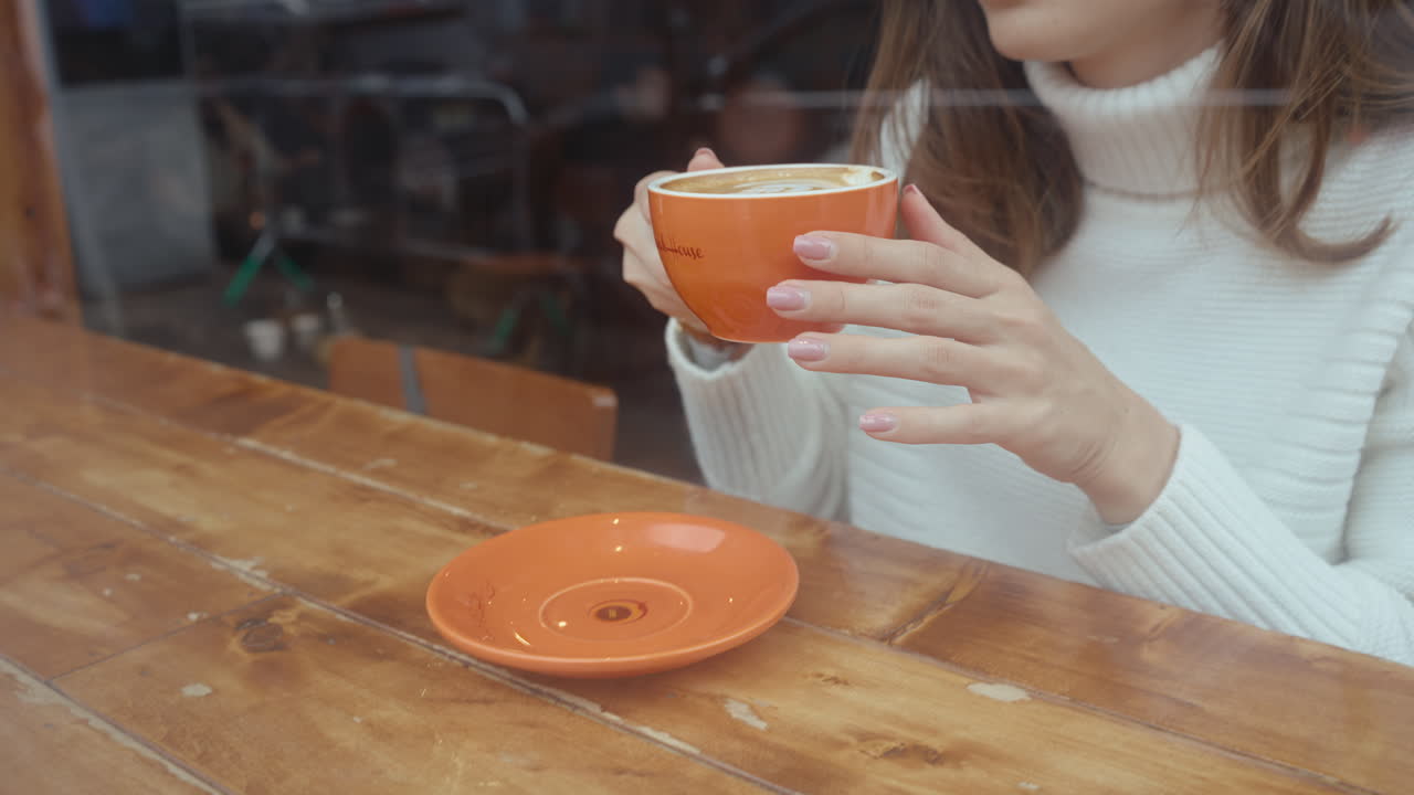 Woman enjoying a warm coffee in a cozy cafe.