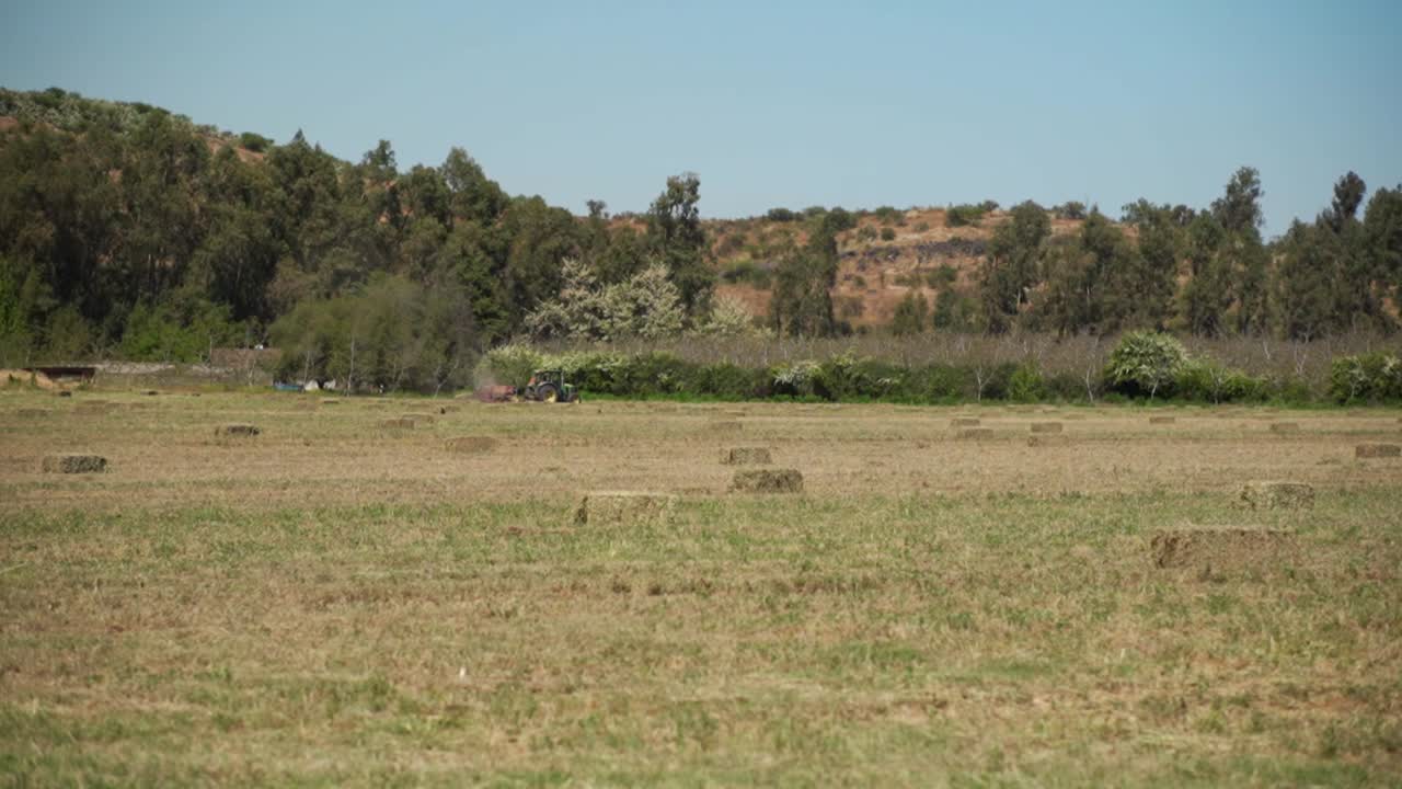 pacas de paja compactadas por un tractor en el fondo, fondo plano con una montaña en el fondo