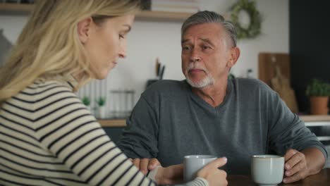 senior man meeting with adult daughter at home.