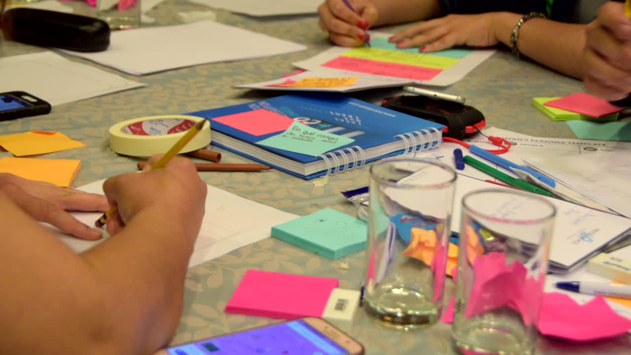 People designing and writing on paper during a ux lean design workshop