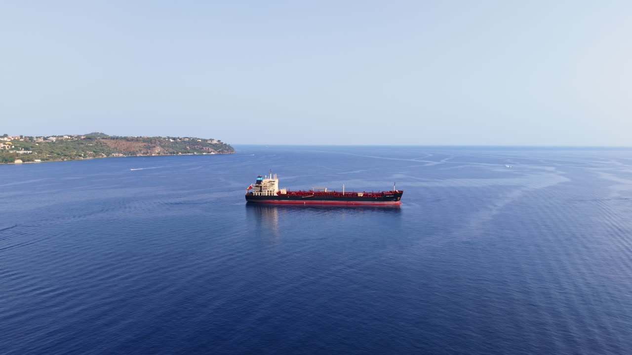 Drone advancing toward a red oil tanker floating offshore, with the Sicilian coastline visible in the background