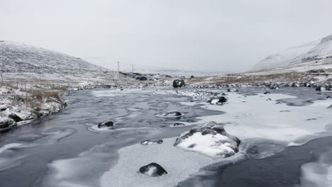 faroe islands, 4k low aerial over beautiful snow covered river