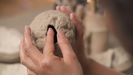 a top view of a professional female potter attentively molding and shaping ceramics oval shaped sculpture. artist working in studio.