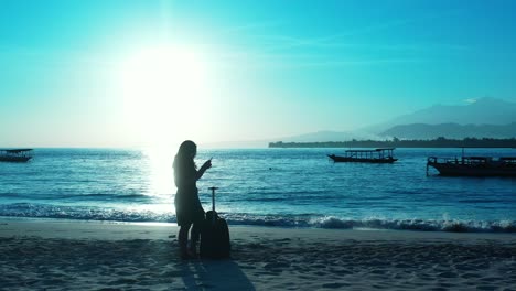 Silueta-De-Mujer-Turista-Con-Bolsa-De-Viaje-Parada-En-Una-Playa-Exótica-Al-Atardecer-Hermoso-Con-Un-Cielo-Brillante-Reflejado-En-Una-Laguna-Tranquila