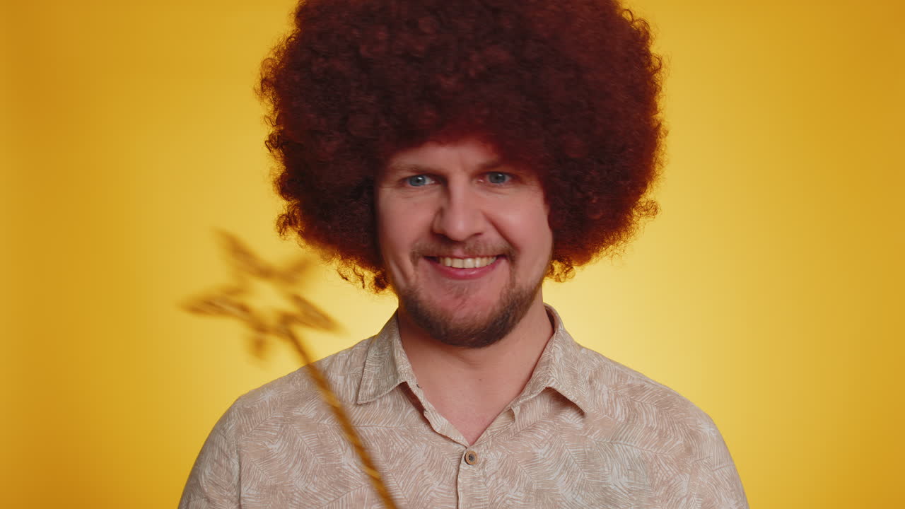 hombre con una peluca afro y una varita de estrella sonriendo