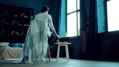 young girl draws a picture on paper. sheet stands on canvas, paints on the table. light room. circular motion of the camera.