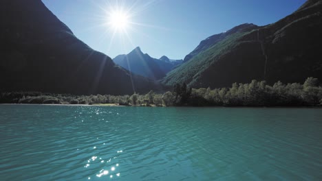 Detailed-shot-of-a-calm-lake,-with-a-sunlit-backdrop-of-mountains-and-trees