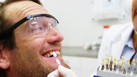Female-dentist-showing-teeth-shades-to-male-patient
