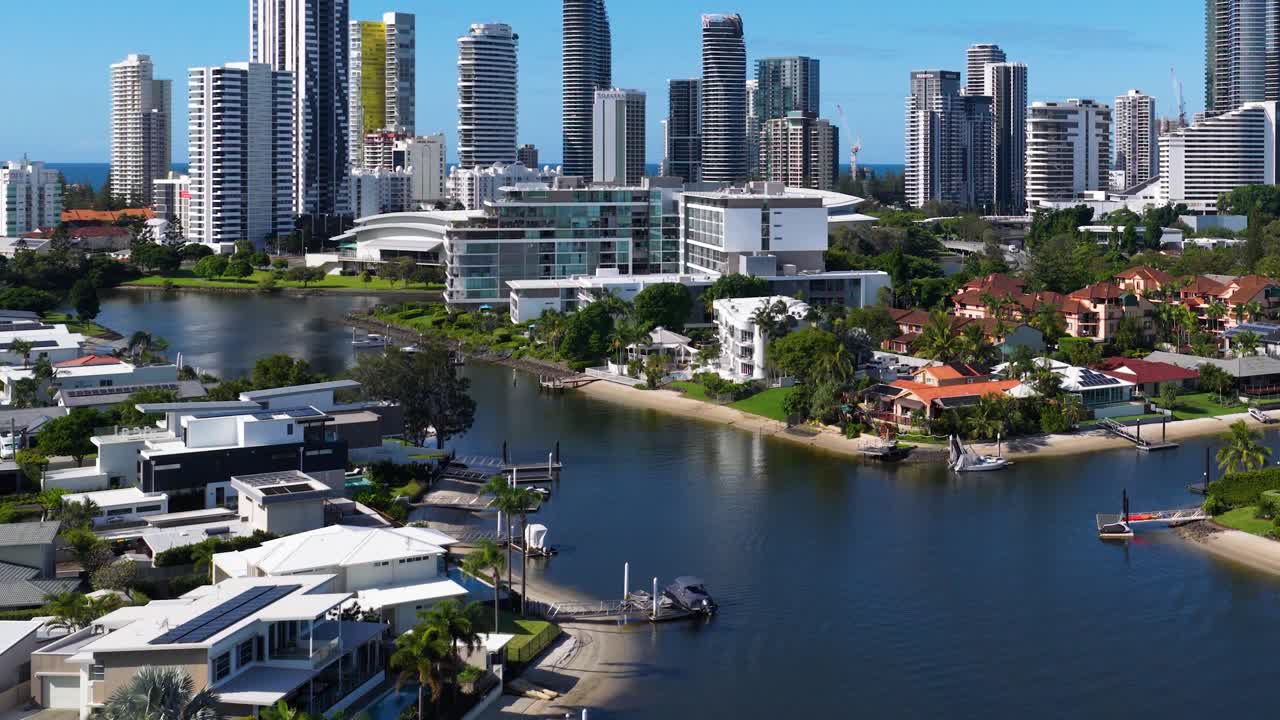 Drone footage captures Gold Coast's skyline and waterways under bright daylight, showcasing urban architecture and natural beauty