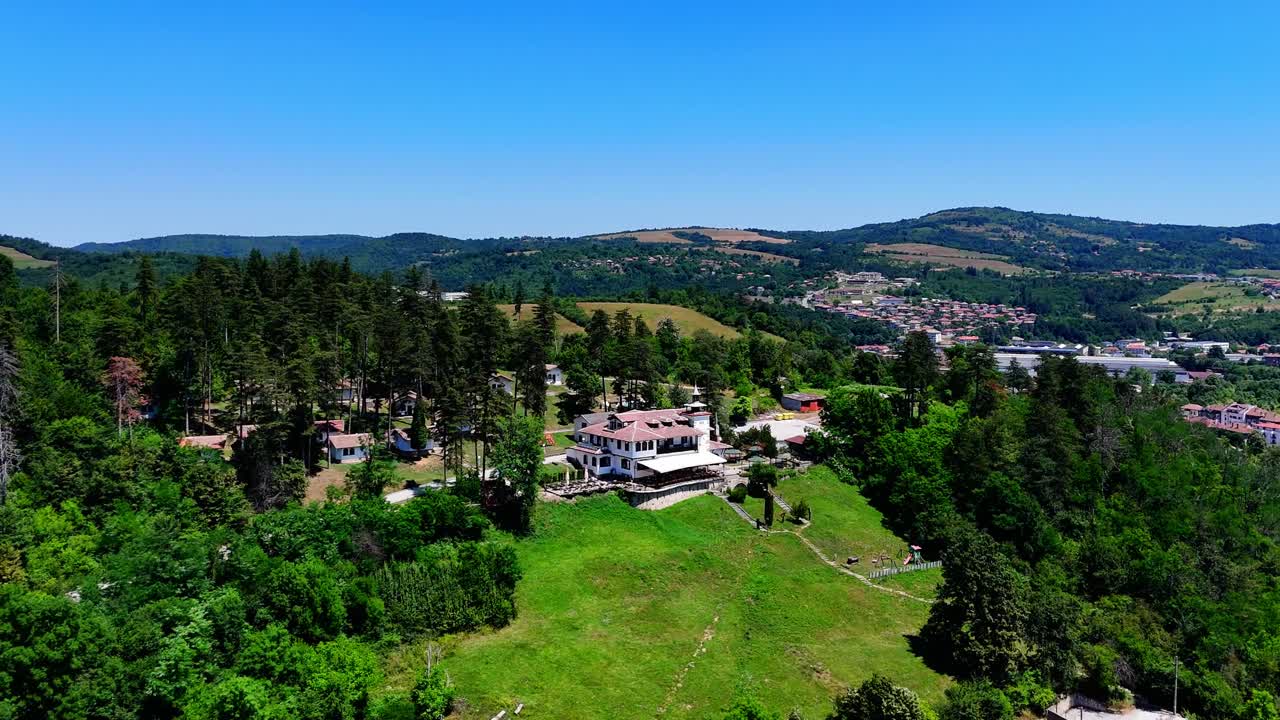 Un drone orbita intorno al complesso di Brushlyan, evidenziandone l'isolamento in cima alla collina con il villaggio di Tryavna adagiato nella valle sottostante