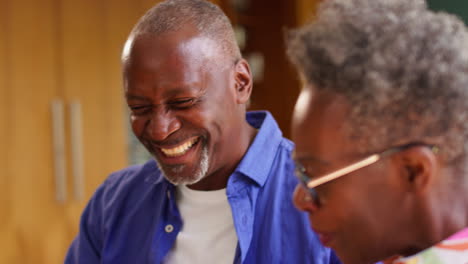 Senior-Couple-Sitting-Around-Table-At-Home-With-Bills-Reviewing-Finances