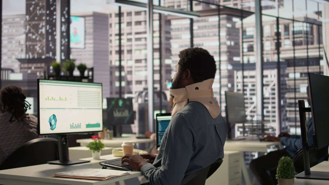 부상당한 사무실 직원이 책상에 앉아 있습니다.